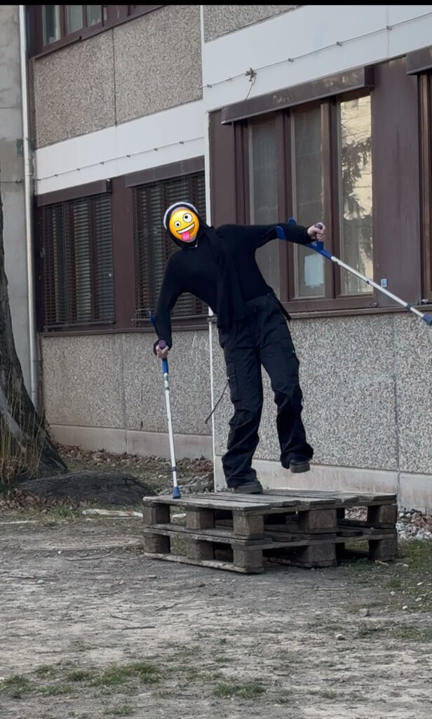 Ein Jugendlicher mit Krücken balanciert auf Holzpaletten.