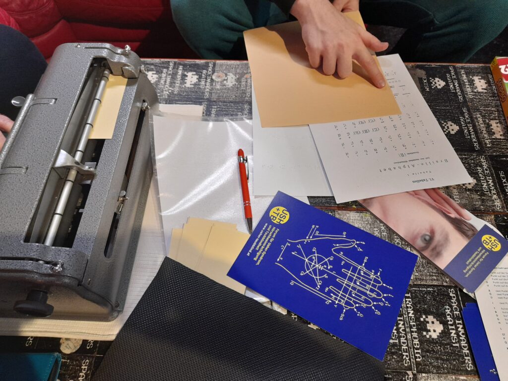 Ein Tisch, auf dem Zettel mit Braille-Schrift liegen.