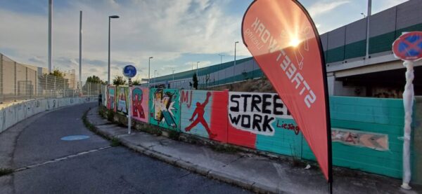 Eine kleine Mauer neben einem Fußgängerweg, die mit Graffitis besprüht wurde.