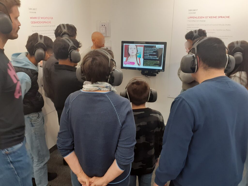 Mehrere Jugendliche stehen vor einem Monitor.