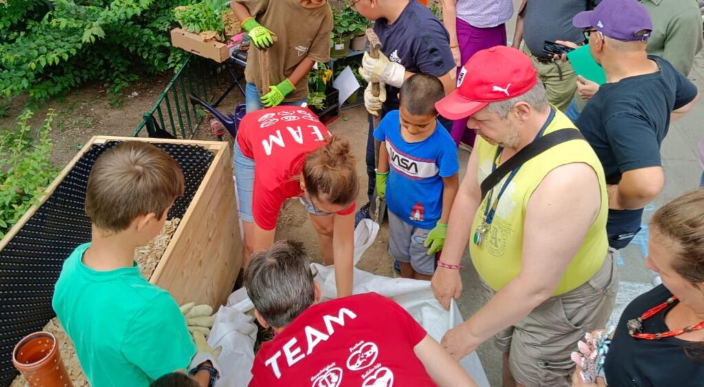 Mehrere Kinder, Jugendliche und Erwachsene befüllen ein Hochbeet.