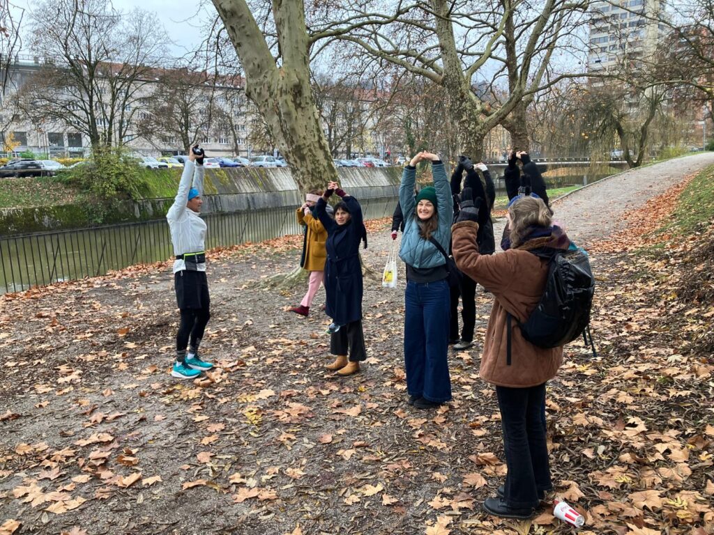 Die Studienreise-Teilnehmer*innen bei Sportübungen in einem Park mit Herbstlaub